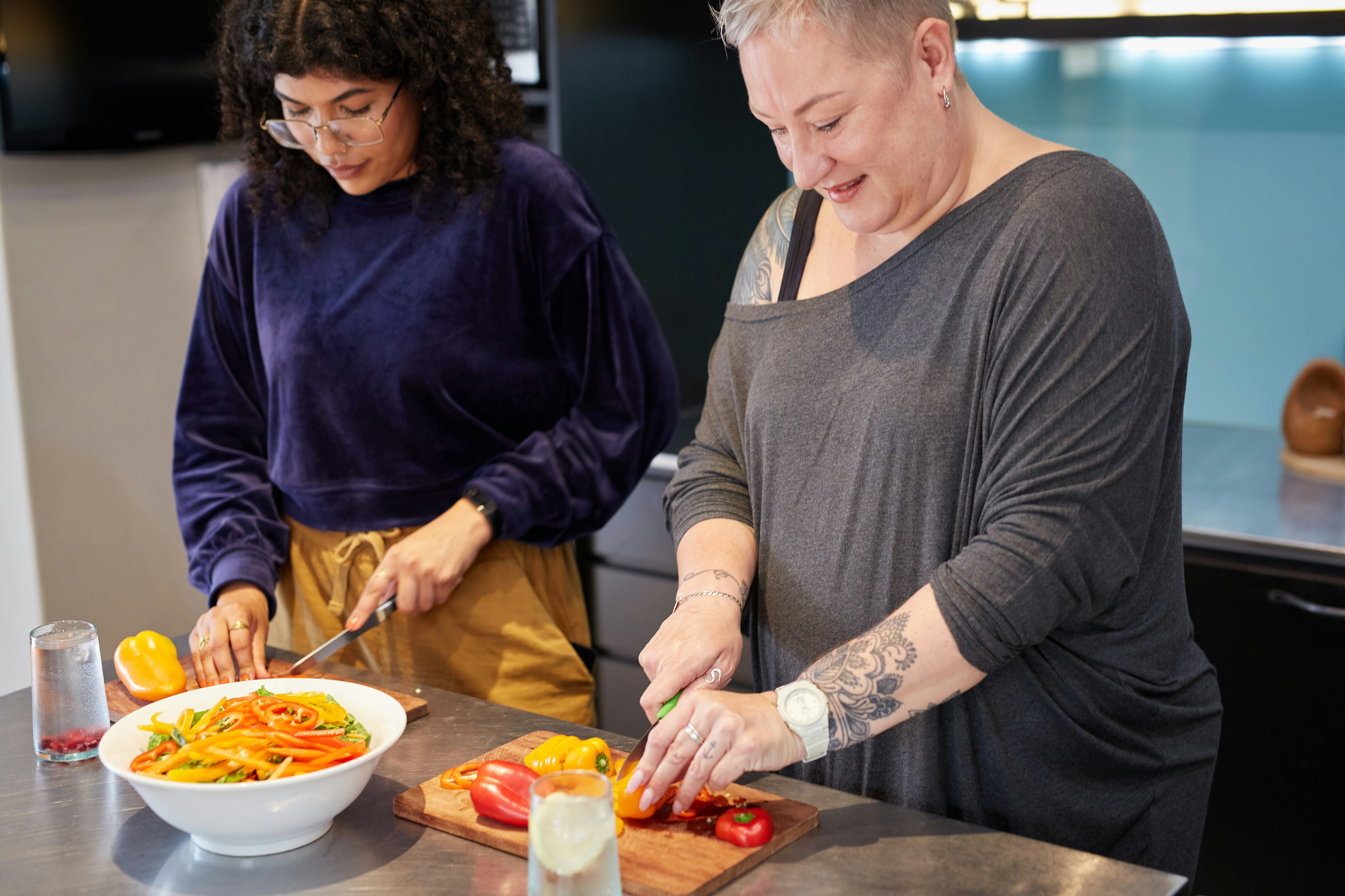 Two women are cooking and chopping vegetables together